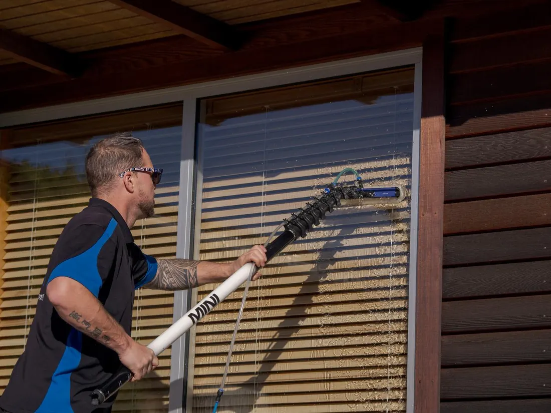 Mike cleaning windows with a water-fed pole at a Wanaka home