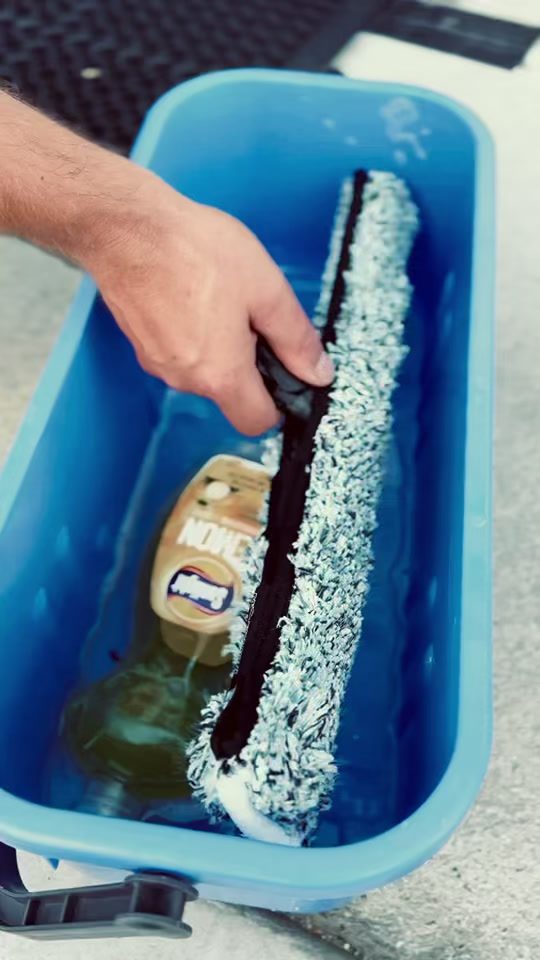 Close-up of a squeegee blade clearing water from glass